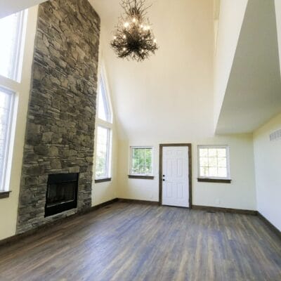 Spacious living room with stone fireplace and high ceiling.