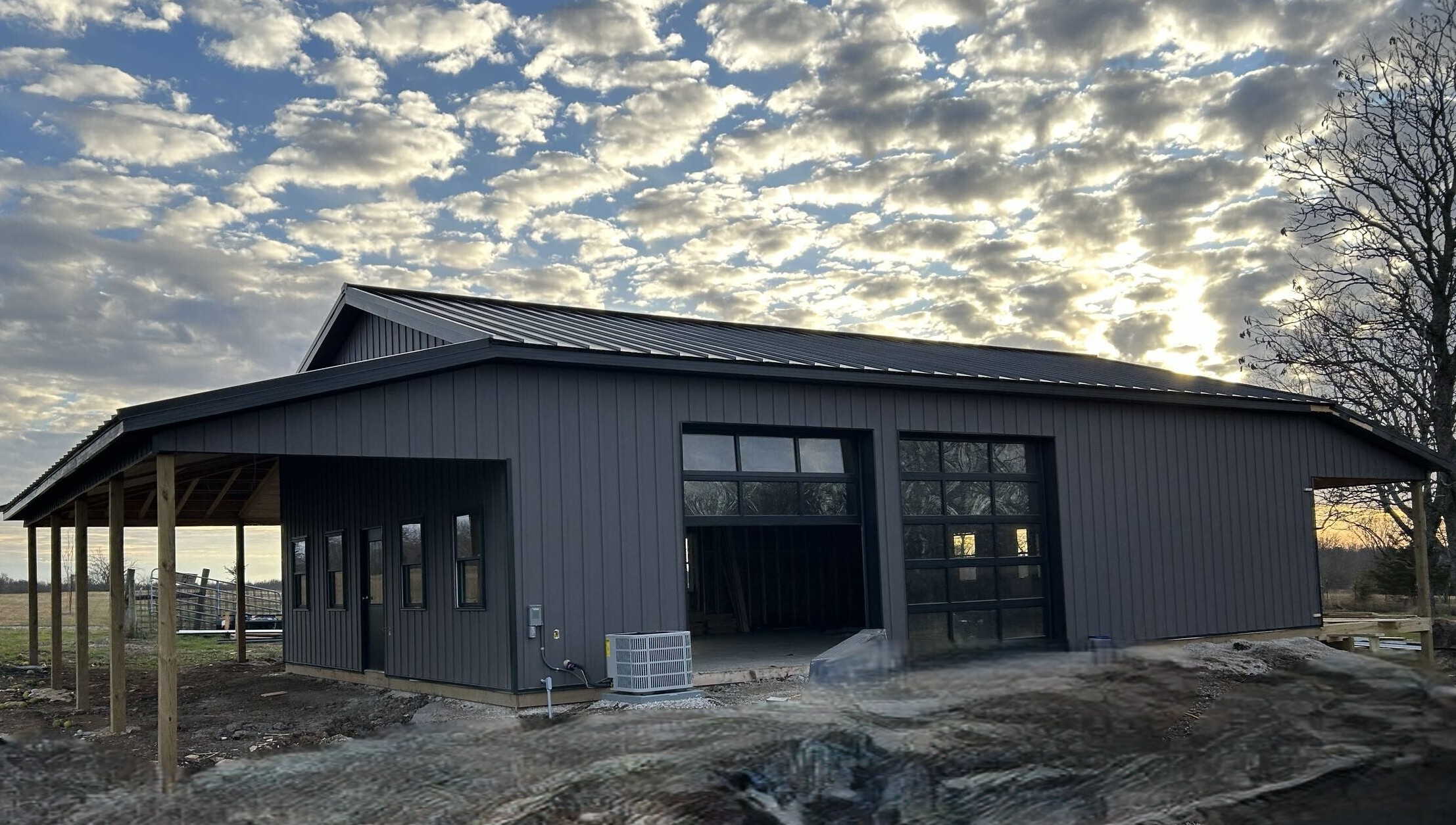Modern barn under cloudy sky at sunset